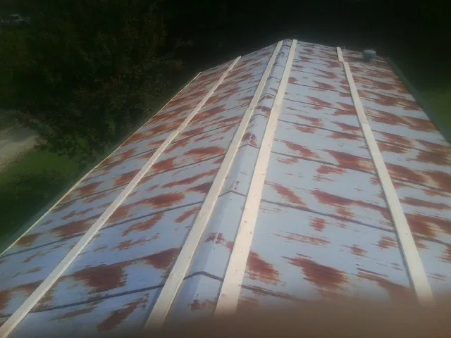 Rusted metal roof panels with new wood purlins before replacement — Storm Damage Roof Repair in Central City by Roofing Brothers