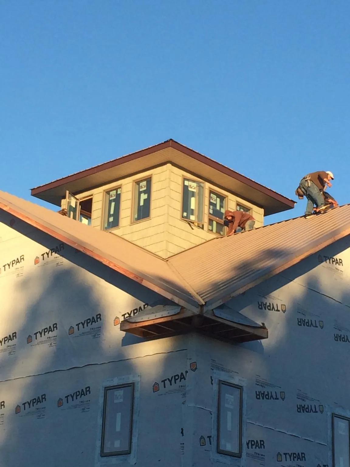 Roofers working around a rooftop cupola on a new metal roof at sunset — Roof Waterproofing in Central City by Roofing Brothers